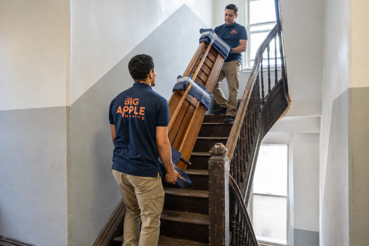 Movers carrying furniture down a Hoboken walk-up staircase