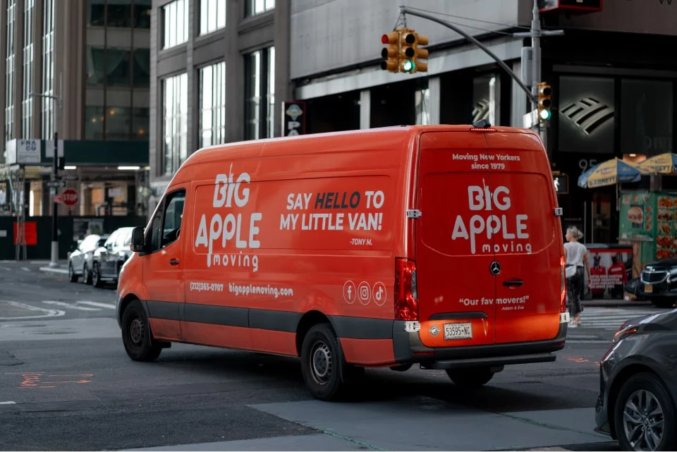 Big Apple Moving van with the company’s orange branding parked on a Manhattan street